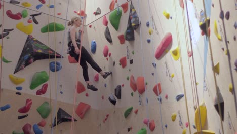 Frau-Steigt-Bunte-Indoor-Kletterwand-Ab,-Kletterhalle