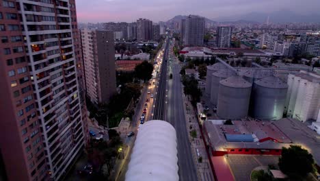 Rodrigo-de-araya-metro-station-at-twilight-with-busy-street-traffic,-aerial-view