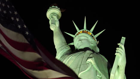Amerikanische-Flagge-Weht-Nachts-Unter-Der-Freiheitsstatue,-Nahaufnahme-Aus-Niedrigem-Winkel