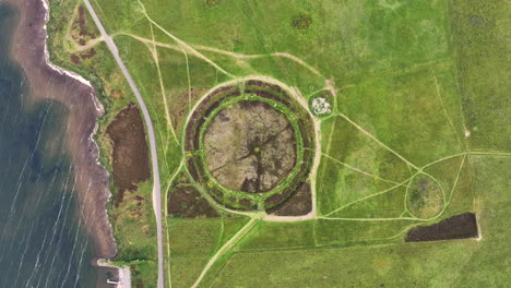 Ring-of-Brodgar,-Birdseye-Aerial-View-of-Prehistoric-Landmark,-Rocks-in-Circle-by-Orkney-Coastline,-Scotland-UK