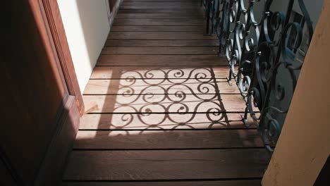 Sunlight-casting-ornate-wrought-iron-shadows-on-a-wooden-walkway-in-Trakoscan-Castle-courtyard