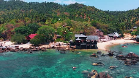 Toma-Aérea-De-Un-Dron-De-Un-Complejo-De-Playa-Tropical-Rodeado-De-Exuberante-Vegetación-Y-Aguas-Cristalinas,-Que-Muestra-Un-Sereno-Paisaje-Costero-En-Tailandia