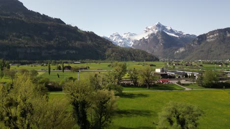 Aerial-Shot-Of-Distant-Weesen-Village,-Snowy-Mountain-In-Background,-St