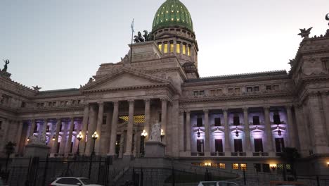 Vista-Nocturna-Del-Edificio-Del-Congreso-Nacional-En-Buenos-Aires-Con-Luces-Violetas-Iluminadas-Y-Un-Telón-De-Fondo-De-Puesta-De-Sol,-Primer-Plano