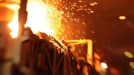 Intense-close-up-of-sparks-flying-from-molten-metal-in-a-foundry,-glowing-warmly