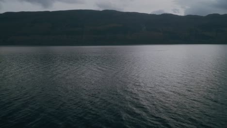 Vuelo-Rápido-Y-Bajo-Sobre-El-Lago-Ness-Con-Vistas-A-Las-Tierras-Altas-De-Escocia,-Plataforma-Rodante-En