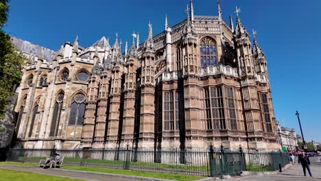 Sunlit-view-of-Westminster-Abbey-with-tourists-and-clear-blue-sky,-wide-shot