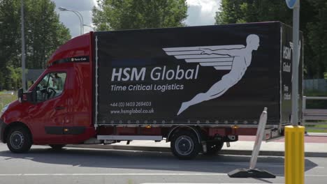 Fleet-of-HSM-Global-delivery-vans-driving-on-road-in-daytime,-tracking-shot