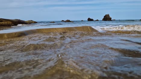 Ocean-waves-eroding-sandy-coastal-beach,-low-angle-view