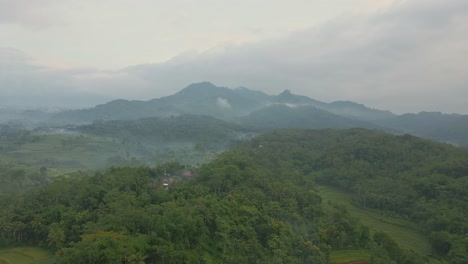 Aerial-view-of-Indonesia-rural-landscape-with-view-of-forest,-village-and-hills-in-foggy-morning