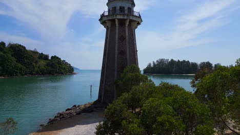 Solitary-lighthouse-on-headland-with-scenic-tropical-beach