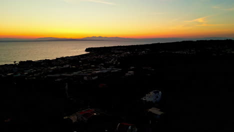 Vibrant-sunset-and-silhouette-of-coastal-city,-aerial-drone-view