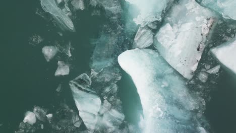 Drone-shot-of-pieces-of-ice-floating-on-water-in-Iceland-during-winter