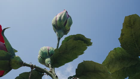 Ant's-view-of-towering-fake-huge-rosebuds-against-a-clear-blue-sky