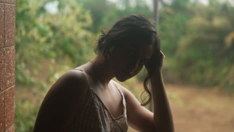 Young-woman-in-contemplation-by-a-window,-tropical-greenery-in-the-background,-indoor,-soft-focus