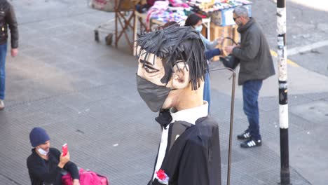 Eine-Riesige-Puppe-Mit-Gesichtsmaske,-Die-Während-Des-Covid-Ausbruchs-Auf-Der-Straße-Läuft