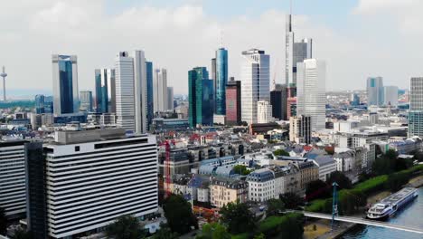 Aerial,-drone-shot-above-main-river,-towards-downtown-Frankfurt,-sunny-day,-in-Germany---Quiet-due-to-the-Coronavirus-pandemic