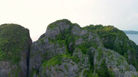 Fly-Up-Over-Mountain-to-Reveal-View-of-Phi-Phi-Island-Seen-From-World-Famous-Maya-Bay-Beach,-Wide-Pan-Left