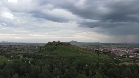 Medellín-Castle,-Spain:-Towering-over-the-Guadiana-River,-its-ancient-stones-stand-resilient-against-a-stormy-sky,-echoing-tales-of-battles-and-conquests