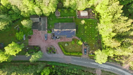 Top-down-drone-shot-of-a-solar-powered-house-in-middle-of-spring-colored-forest