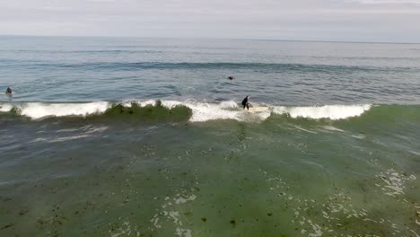 Drone-footage-of-a-surfer-getting-up-and-riding-an-approaching-wave-on-a-Rhode-Island-beach