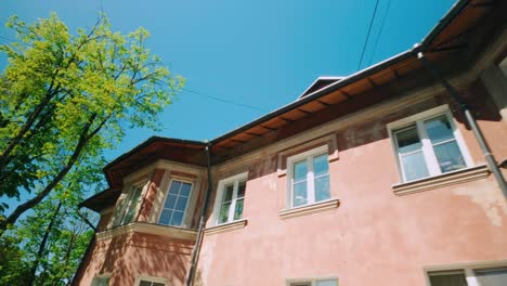 Die-Kamera-Gleitet-Im-Sonnigen-Frühling-An-Einer-Funky-Pastellrot-rosa-Hausfassade-Vorbei