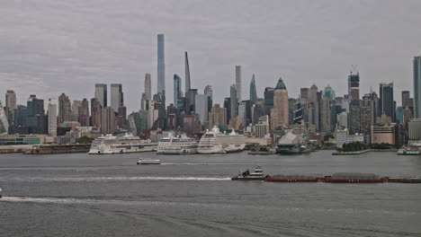 Nueva-York-Nueva-York-Aérea-V217-Sobrevuelo-Del-Río-Hudson-Capturando-Una-Barcaza-De-Remolque-En-La-Vía-Fluvial,-Los-Muelles-Frente-Al-Mar-En-Hell&#39;s-Kitchen-Y-El-Paisaje-Urbano-Del-Centro-De-Manhattan---Filmado-Con-Inspire-3-8k---Septiembre-De-2023