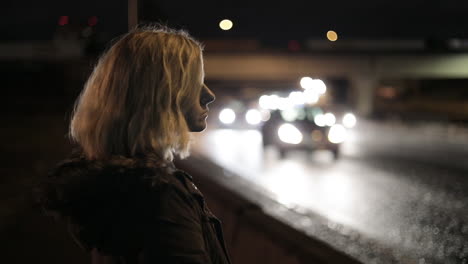 A-girl-stands-by-a-highway-at-night