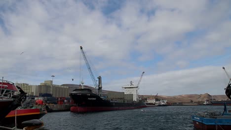 A-cargo-ship-at-port,-loading-and-unloading-shipment-in-Madeira---wide-shot