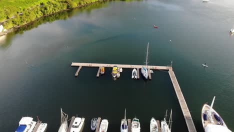 Drone-footage-of-a-SUP-boarder-paddling-on-river-in-a-sunny-day-entering-marina-with-yachts