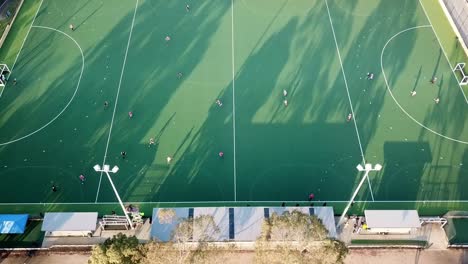 Panorámica-Hacia-Abajo-Y-Hacia-Afuera-De-Imágenes-De-Drones-Sobre-El-Partido-De-Hockey-Sobre-Césped-De-La-Liga-Principal-Masculina-En-El-Parque-Elgar