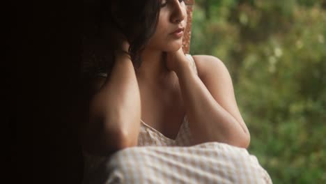 Young-beautiful-woman-adjusting-hair-in-a-rustic-setting,-gentle-and-intimate-moment-captured-in-natural-light