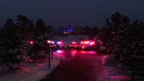 Back-out-aerial-view-of-emergency-vehicles-parked-at-snowy-rural-intersection