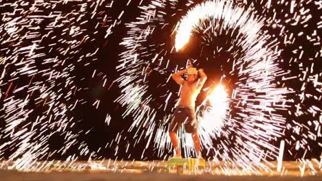 A-thai-man-stanindg-on-a-small-stand-spins-the-steel-wool-with-his-two-arms-creating-countless-amounts-of-sparks-around-him-brighting-up-the-area-around-him-and-entertaining-crowds-of-tourists