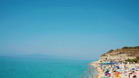 Beach-Tropea---People---Bathers-enjoying-the-sun---Sky-to-Beach---Camera-pan-from-the-Blue-Sky-on-Beautiful-Beach---slow-motion