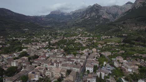 Drone-Shot-of-Tranquil-Mountain-Village-Amidst-Rugged-Hills-of-Soller-in-Mallorca,-Spain