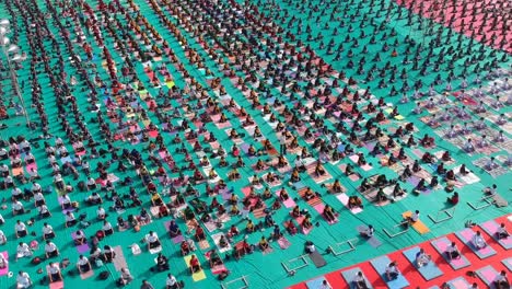 Aerial-footage-of-people-performing-Yoga-in-a-stadium-at-Ahmednagar,-India-on-the-occasion-of-International-Yoga-Day-along-with-school-students