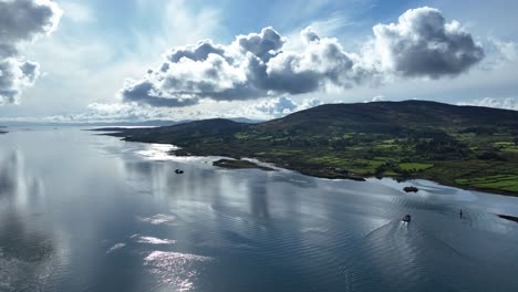 Drone-dramatic-early-morning-skies-over-Bere-Island-in-west-Cork-Ireland-on-the-Wild-Atlantic-Way-with-calm-waters-and-small-boat