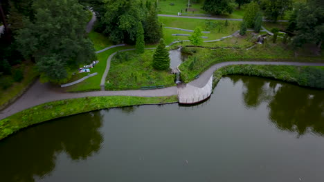 Drone-Volador-Rápido-Que-Sube-Por-Encima-De-Un-Gran-Parque-Con-Un-Estanque,-Parque-Urbano-Berg-En-Bos-En-Apeldoorn