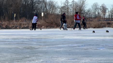 A-bottom-up-action-following-shot-of-group-of-individuals-playing-pond-hockey