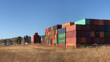 Slow-Motion-Steady-Shot-during-Sunset-Golden-Hour-of-containers-on-the-background-and-yellow-grass-on-the-foreground