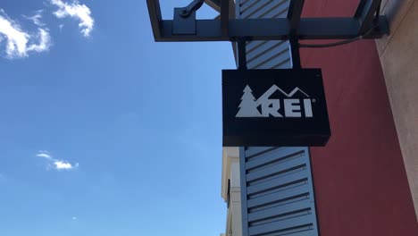 An-Exterior-sign-for-an-REI-outlet-store-in-a-mall-in-the-Pacific-Northwest-on-a-clear,-sunny-day-with-blue-skies-and-minimal-clouds