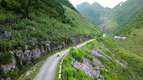 Aerial-drone-shot-view-of-Vietnamese-locals-along-an-old-road-with-the-valley-and-mountain-peaks-in-the-distance