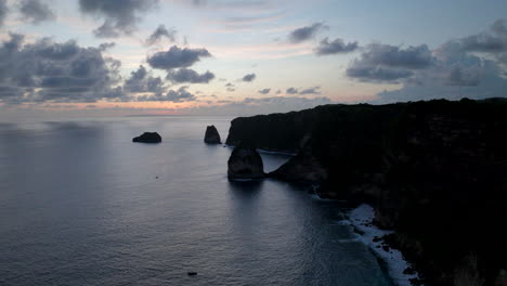 Grey-skyline,-distant-sunset,-landscape-silhouette,-calm-ocean-water