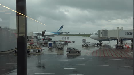 Dolly-Truck-on-planes-and-vehicles-at-work-on-the-pavement-Tarmac-at-Paris-Orly-airport-before-takeoff,-view-from-boarding-zone