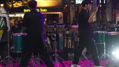 Back-view-of-two-men-playing-drums-instruments-on-stage-in-the-front-of-audience-on-music-festival