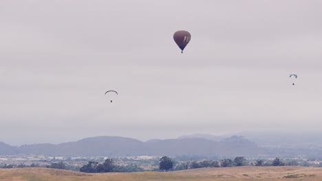 Temecula-Ballon--Und-Weinfest,-Drohnenansicht-Des-Pala-Heißluftballons-Mit-Zwei-Gleitschirmen,-Einer-Fliegt-Rechts-Aus-Dem-Rahmen