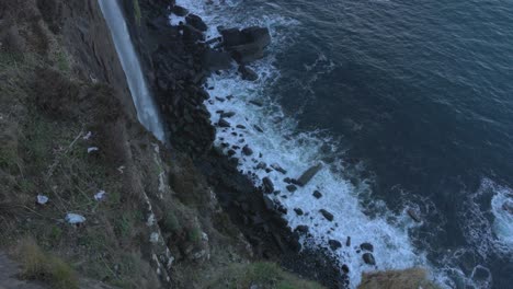 Top-down-shot-of-the-waves-crashing-on-the-beach-below-the-Mealt-Falls