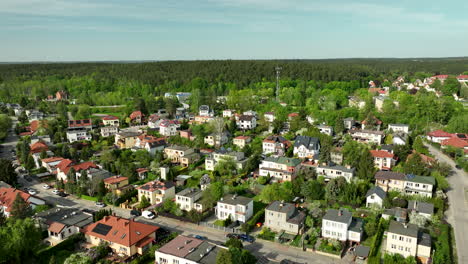 An-aerial-view-of-a-residential-area-in-Olsztyn,-showing-houses-with-red-and-gray-roofs-surrounded-by-green-trees-and-vegetation