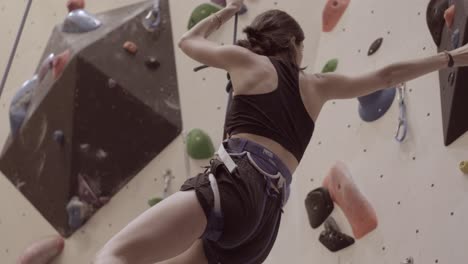 Woman-Climbing-and-reaching-the-top-of-a-outdoor-bouldering-wall-with-a-rope